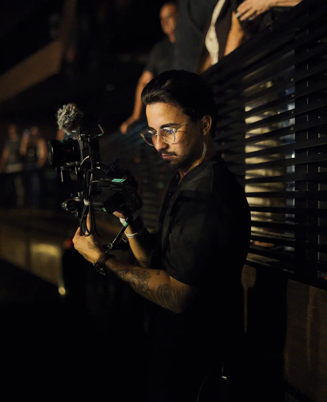 Operador de gimbal filmando na lateral do palco sob luz quente