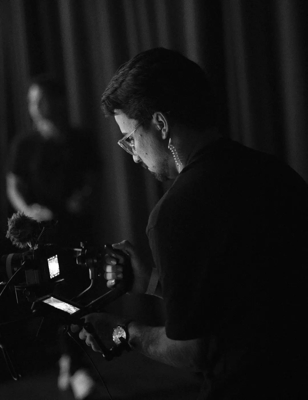 Cinegrafista de perfil com câmera, em preto e branco