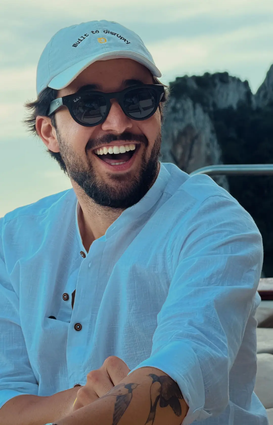 José Lucas sorrindo no barco, de boné Built to Disrupty, em Capri