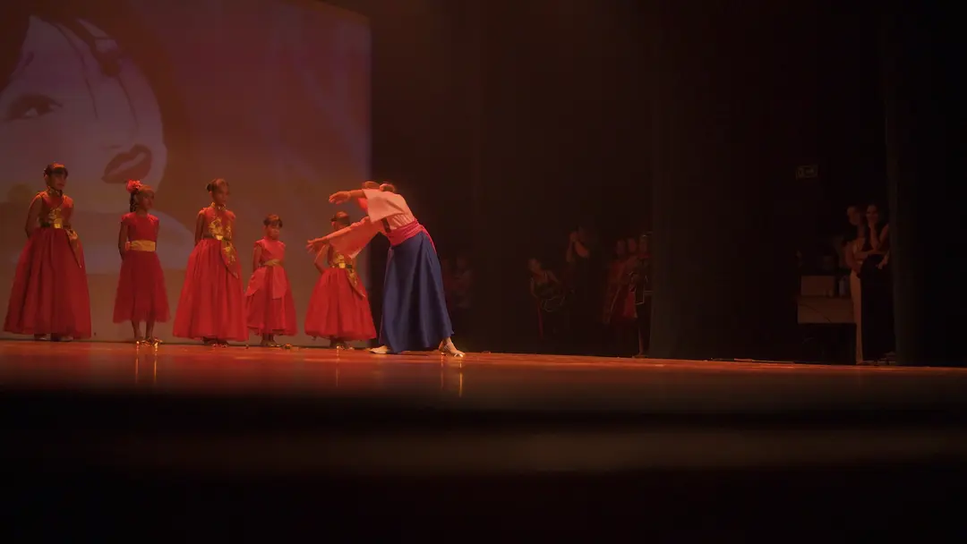 Bailarinas de vestido vermelho diante do telão